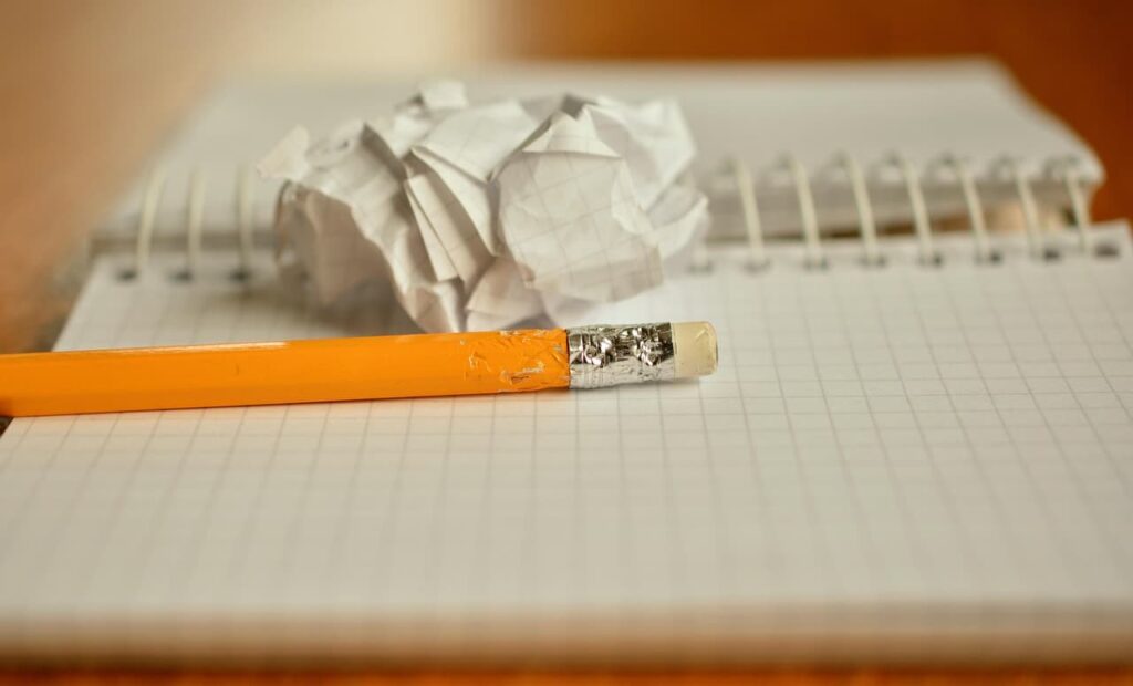 A notebook, a pencil, and a single crumpled sheet of paper.