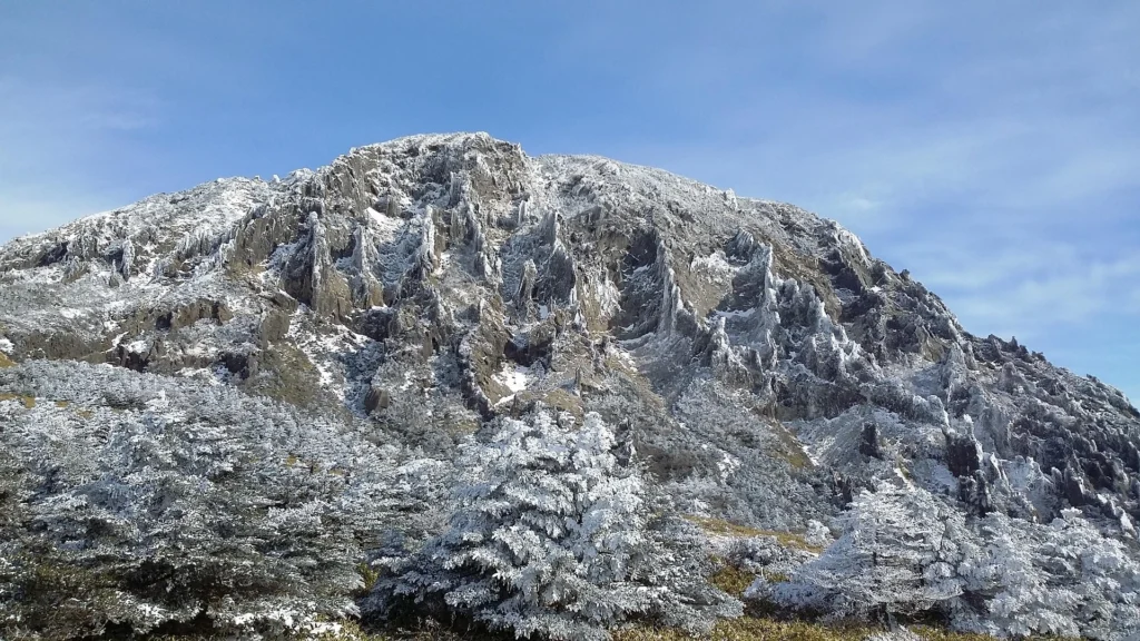 Snow-covered Baengnokdam crater at the summit of Hallasan Mountain, serene and pristine under a winter sky.