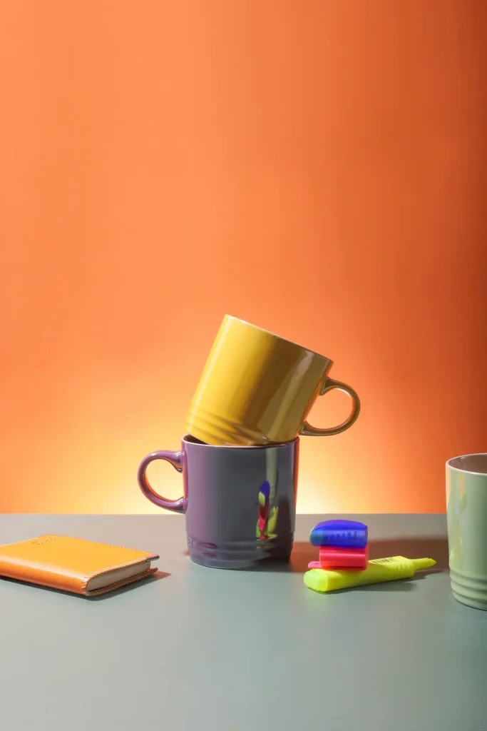 Yellow and purple cups with a notebook on a desk.